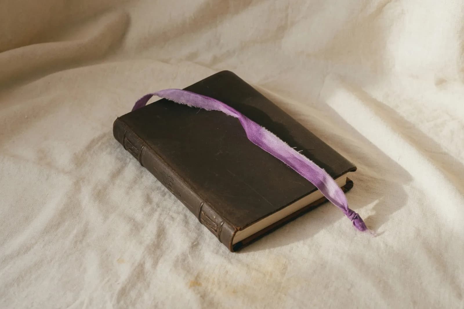 Worn leather journal with a soft purple ribbon bookmark